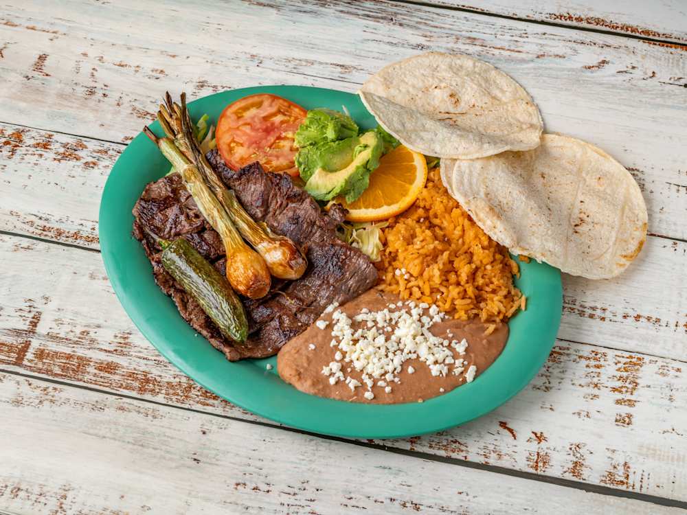 Carne asada platillo — char-broiled skirt steak with rice, beans and tortillas